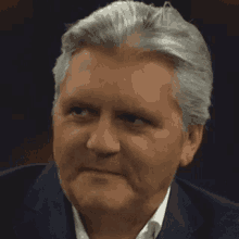 a man with gray hair is wearing a suit and white shirt .