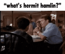 a man is sitting at a table talking to another man with the words " what 's hermit hamlin " above him