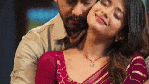 a man and a woman are hugging each other with their eyes closed .
