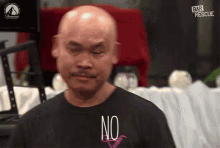 a bald man wears a black shirt that says no