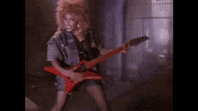 a woman with a mohawk is playing a red electric guitar .