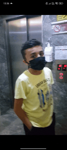a man wearing a mask and a yellow shirt stands in an elevator ..