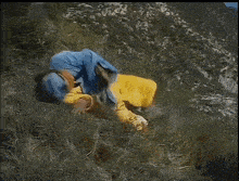 a person in a blue jacket and yellow pants is laying on their back