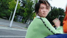 a man wearing a green sweater is walking down a street