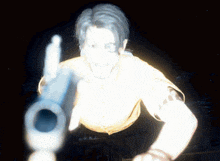 a man in a yellow shirt is pointing a gun at something