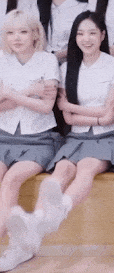 two girls in school uniforms are sitting next to each other on a bench with their legs crossed .