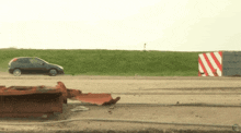 a car is driving down a road next to a red and white striped object