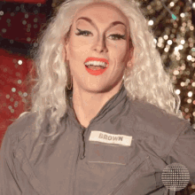a drag queen with blonde hair and a name tag that says brown on it
