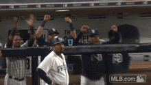 padres baseball players celebrate in the dugout with mlb.com in the background