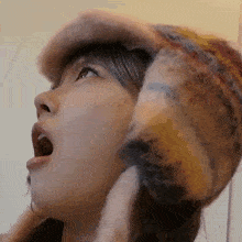 a close up of a woman wearing a furry hat with her mouth open