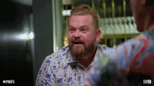a man with a beard is wearing a floral shirt with the number 9 on it