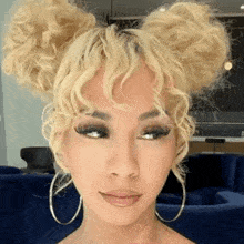 a woman with blonde curly hair is wearing hoop earrings