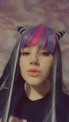 a girl with pink and blue hair is blowing a kiss
