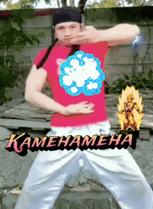 a man in a red shirt and white pants is standing in front of a fence with the word kamena on the bottom right