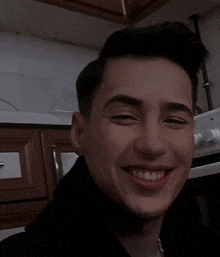 a young man is smiling in front of a stove with the words oc ugur written above him