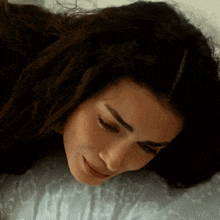 a close up of a woman laying on a bed with her eyes closed