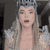 a woman in a costume with a crown on her head is making a surprised face