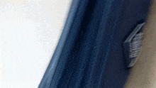 a blue curtain is hanging on a window with a white wall in the background