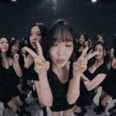 a group of young women in black dresses are giving the peace sign