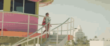 a woman is standing on the stairs of a lifeguard tower on the beach