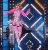 a drag queen is dancing on a stage in front of a blue wall .