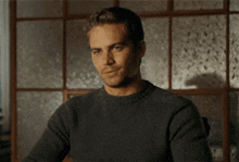 a man in a grey sweater is smiling and giving a thumbs up
