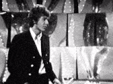 a man in a suit stands in front of a bbc four advertisement
