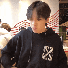 a young man wearing a black hoodie with a white x on the back
