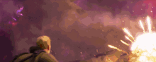 a man is standing in front of a large explosion with a purple background .