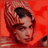a woman wearing a red and gold helmet looks at the camera .