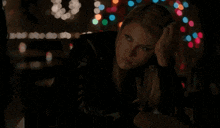a woman in a black leather jacket is standing in front of a christmas tree .