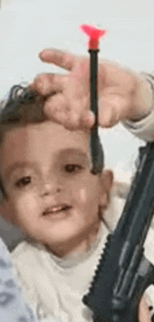 a little boy is holding a gun and a dart in his hand .