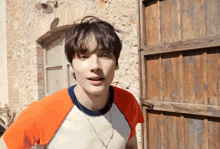 a young man standing in front of a wooden door with his mouth open