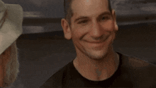 a man wearing a hat and a black shirt smiles at another man