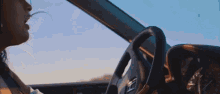a woman is driving a car with a steering wheel that has the letter t on it