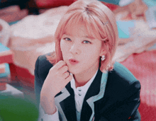 a girl with pink hair and a ring on her finger looks at the camera
