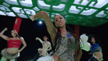 a group of women are dancing in front of a green light