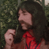 a man with long hair is smoking a pipe