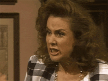 a woman wearing a plaid shirt and a gold necklace