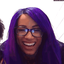 a woman with purple hair and glasses is smiling and laughing .