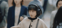 a woman wearing headphones is walking through a crowd of people in a city .