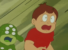 a boy in a red shirt is standing next to a green monster with white eyes