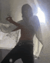 a man without a shirt is dancing in front of a white curtain