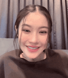 a close up of a woman 's face with a gray curtain in the background