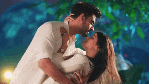 a man is kissing a woman on the forehead while they are hugging