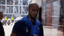 a man wearing earbuds and a blue adidas shirt