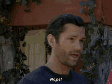 a man with a beard says nope in front of a wooden building