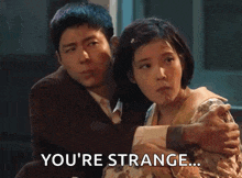 a man is hugging a woman with the words `` you 're strange '' written next to them .