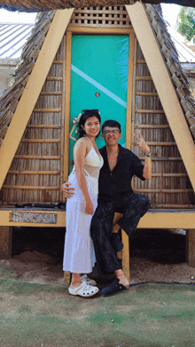 a man and woman pose in front of a thatched hut that says masisa