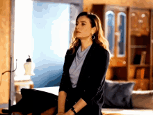 a woman wearing a black jacket and earrings is standing in a living room